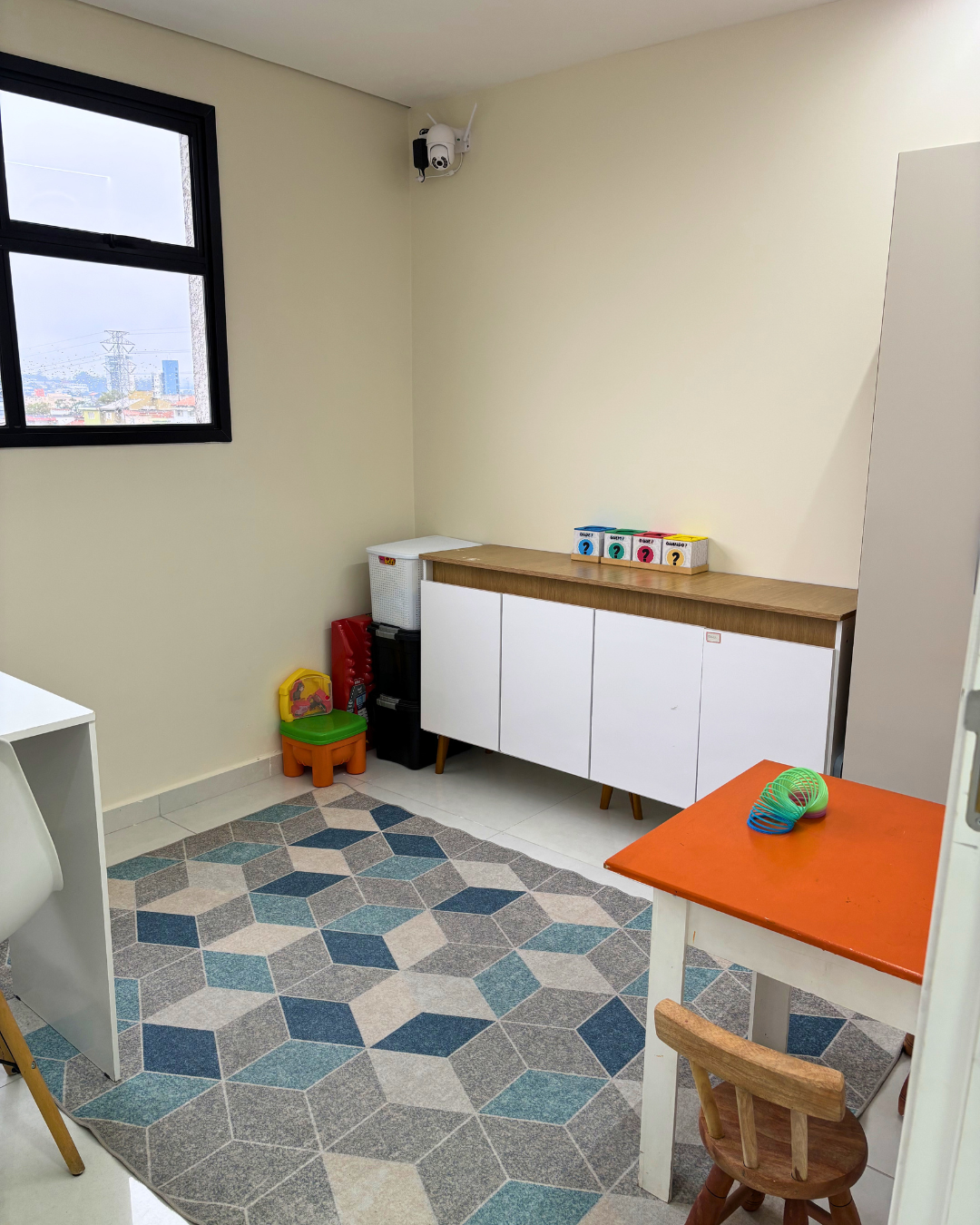 Sala de terapia com tapete colorido e materiais organizados