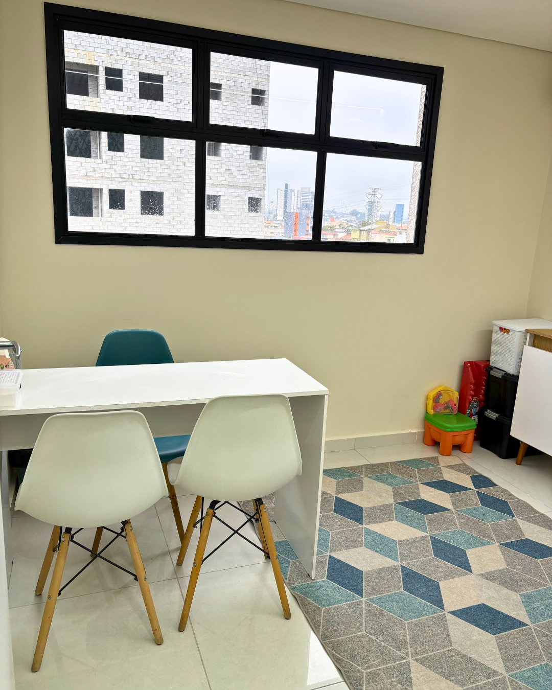 Sala com mesa, cadeiras e vista pela janela na Clínica Almeida